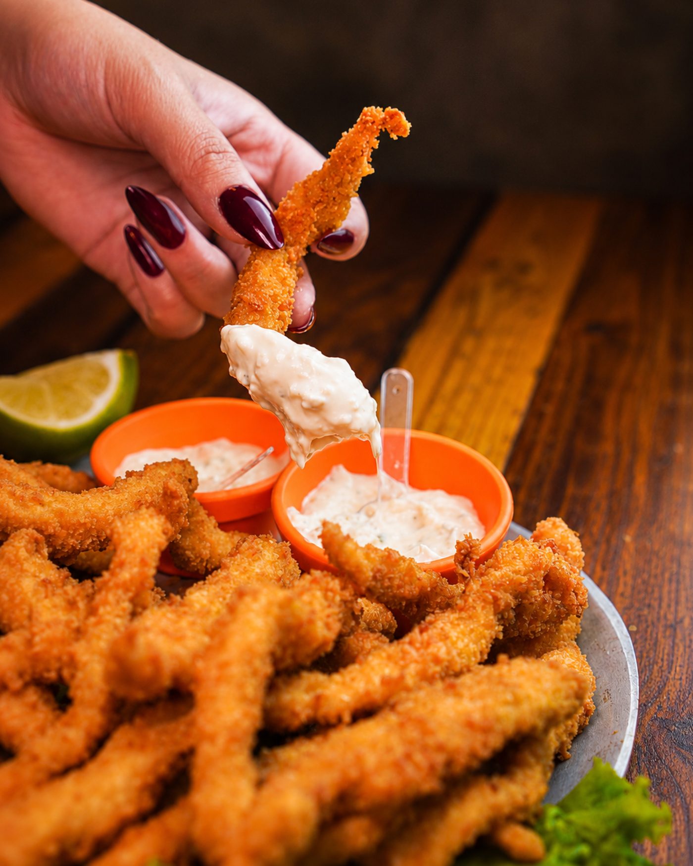 Porção de iscas de peixe empanadas com molho tártaro e limão
